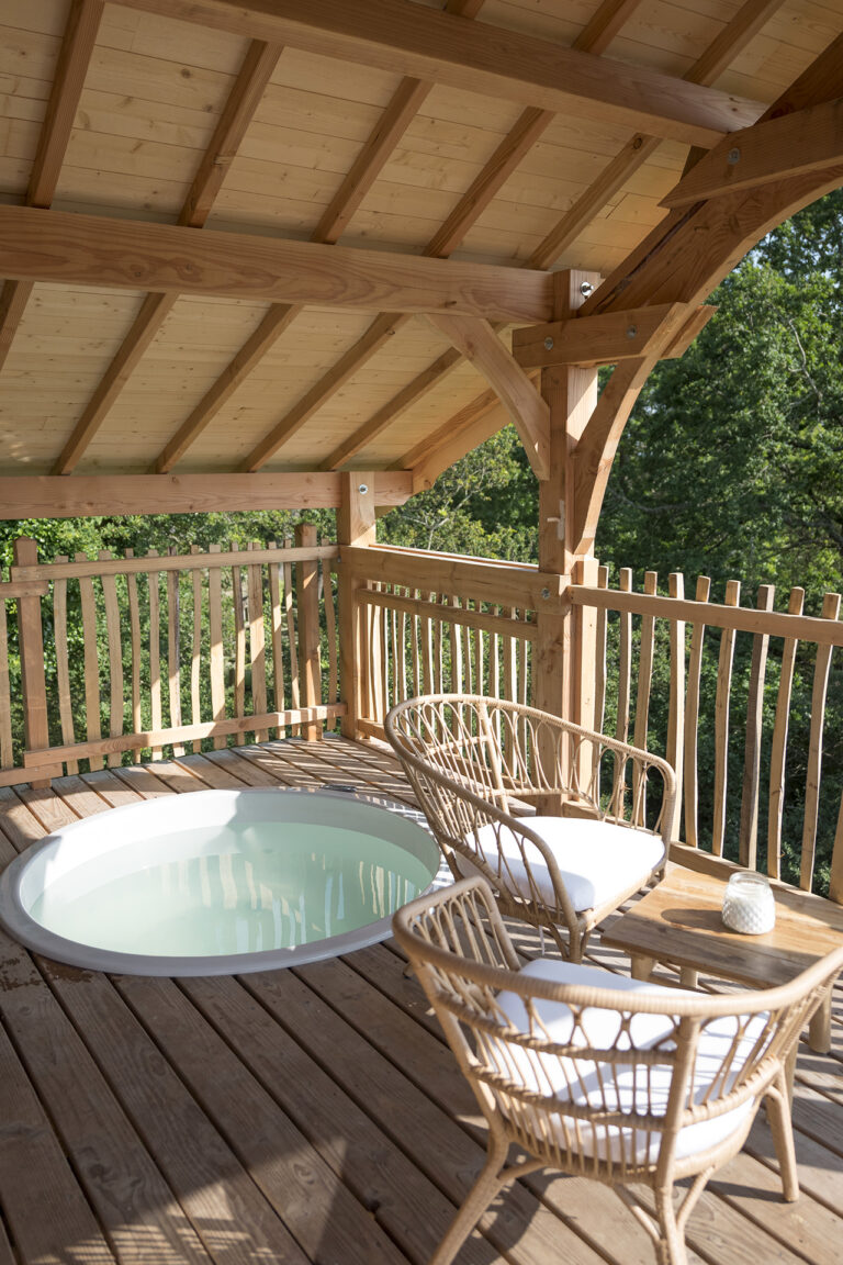Jacuzzi et fauteuils sur la terrasse couverte de la cabane Ehan