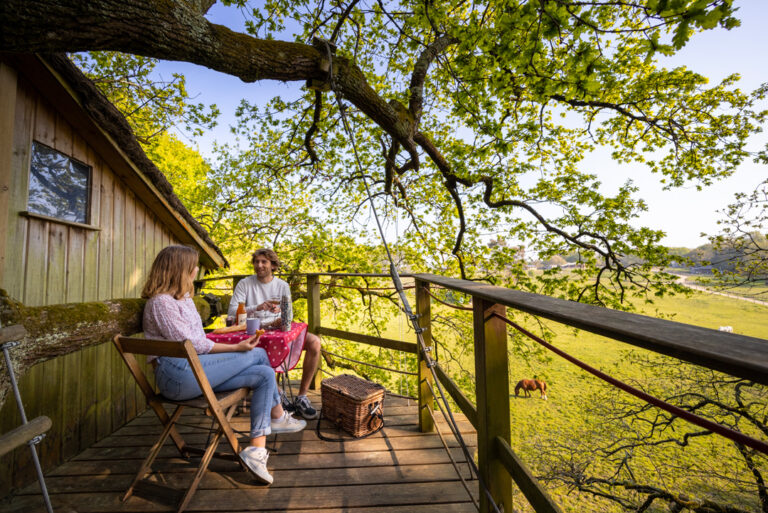 Un couple prend le petit-déjeuner sur la terrasse de la cabane Nijal, face à la prairie